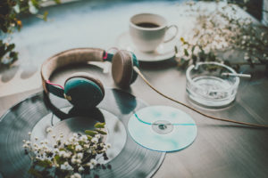 Table with headphone, LP, CD, coffee and cigarette and white flowers
