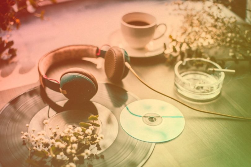 Table with headphone, LP, CD, coffee and cigarette and white flowers